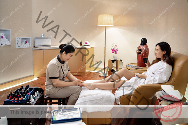 Nhân viên spa mặc đồng phục giản dị, gọn gàng làm móng cho khách hàng